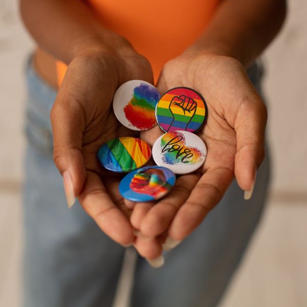 A pair of hands cups themselves around a pile of colorful buttons to decorate an article of clothing with