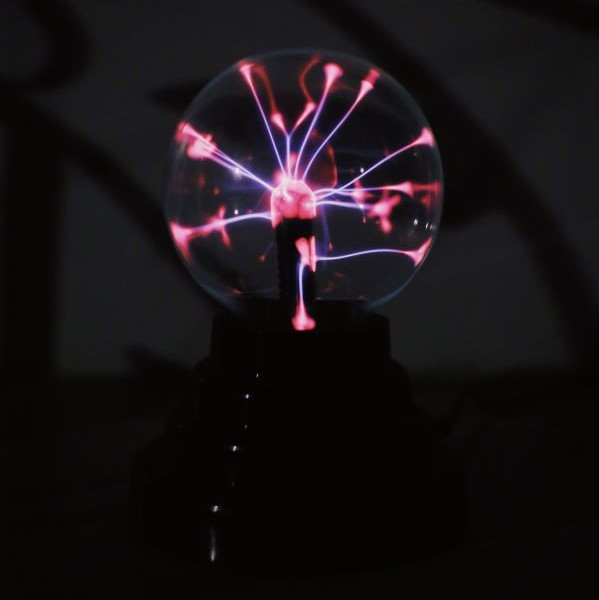 A glowing glass orb with streams of neon color that originate in the center and spread out to touch the walls.